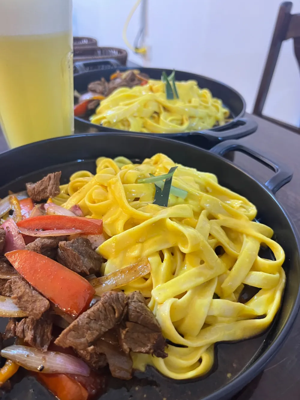Fetuccini a la huancaína con lomo saltado servido en sartén