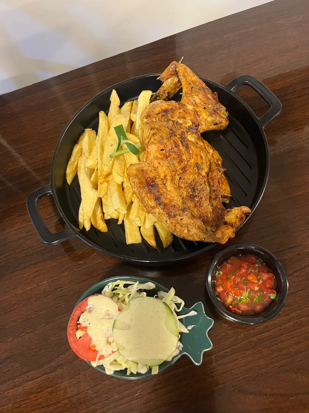 Pollo a la parrilla con papas fritas, ensalada y salsa criolla