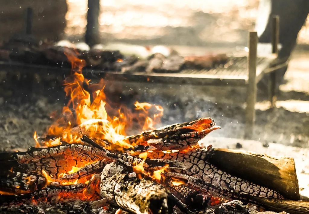 Leña encendida y brasas listas para la parrilla
